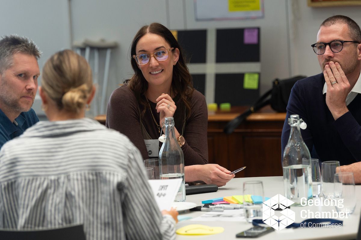 Participants at an Arena session sit around a table with sticky notes, listening and discussing a scenario