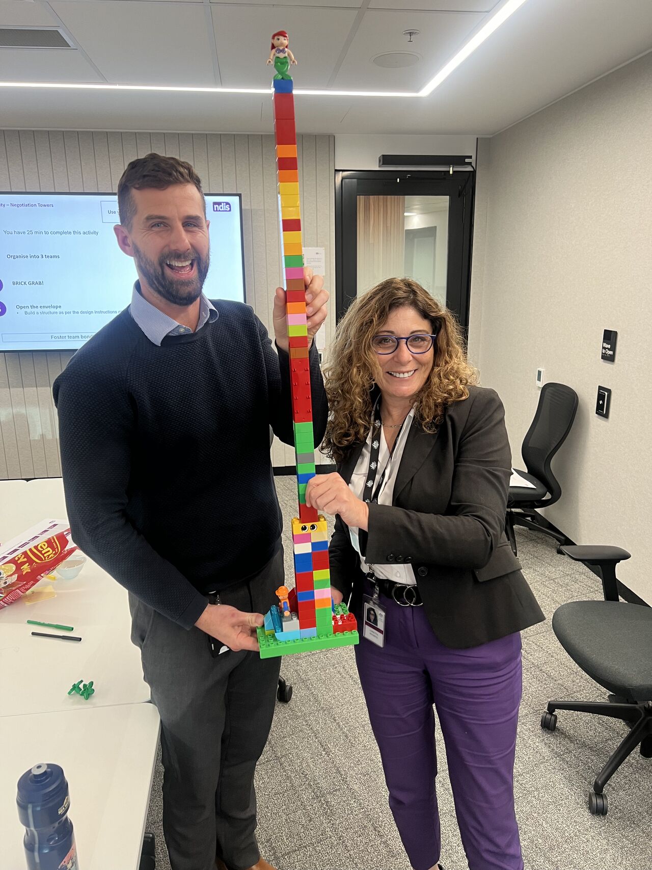 Two participants laughing while holding a hands-on build from a Straforma exercise