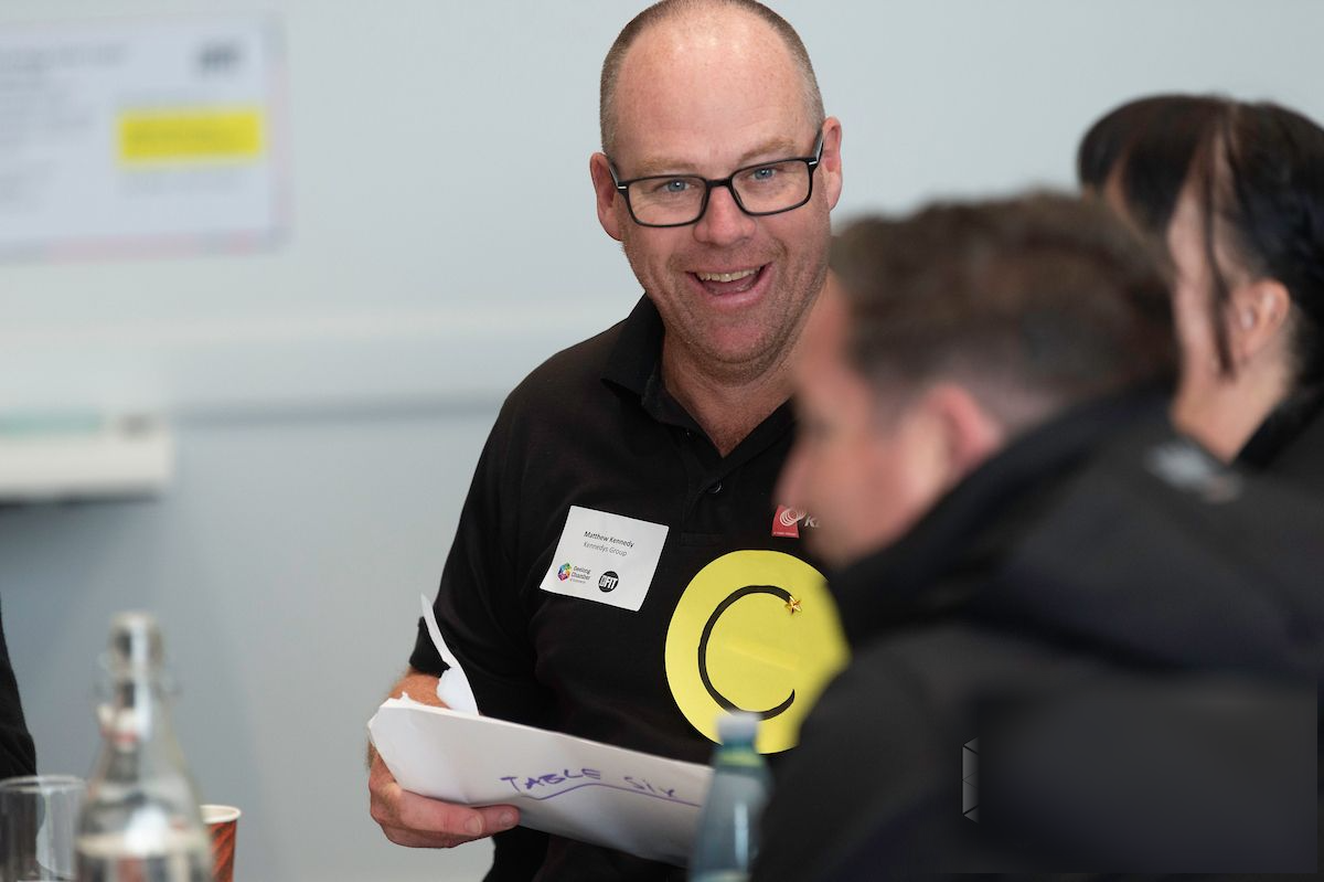 A participant holding a handwritten table sheet mid-discussion