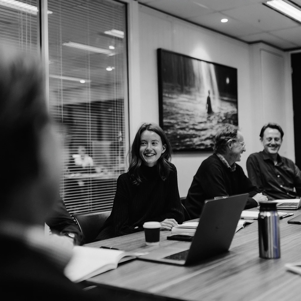 A leadership team laughing together around a boardroom table